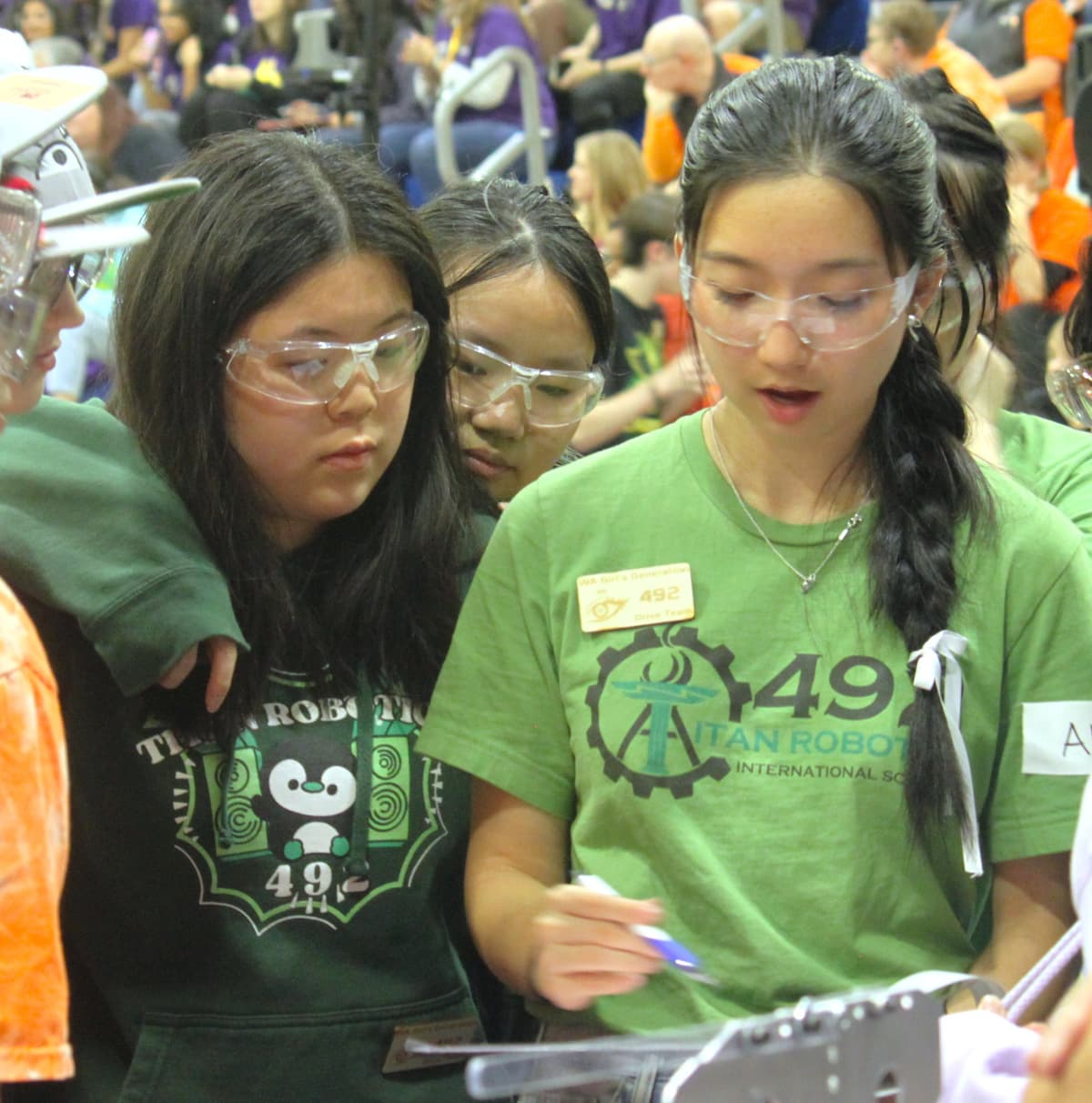 Students looking over at a clipboard while strategizing.